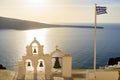 Bell tower and national flag of Greece in sunset light in Oia, Santorini, Greece Royalty Free Stock Photo