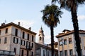 Bell tower among old houses and palm trees in the town of Menaggio. Lake Como, Italy Royalty Free Stock Photo