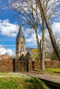 Bell tower of St. Michael Abbey church against blue sky with white clouds, surrounded by houses Royalty Free Stock Photo