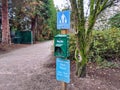 View of a doggie bag station at the downtown Bellevue Park, with the park hours posted below