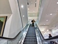 Woman riding an escalator up to the second floor of a large department store inside the Royalty Free Stock Photo