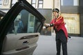 Bellman in red jacket opens limo door in front of Helmsley Park Lane Hotel on Central Park West, in Manhattan, New York City, NY