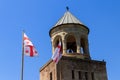 Bells tower of Svetitskhoveli Cathedral and Georgian flag against blue sky in Mtskheta, Georgia Royalty Free Stock Photo