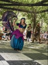 Belly dancer in motion with costumed musicians in vine covered alcove at Renassiance Festival in Muskogee Oklahoma USA 5 28 2017
