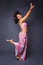 Belly dancer performing belly dance in the ethnic pink costume for dancing on gray background Royalty Free Stock Photo