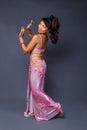 Belly dancer performing belly dance in the ethnic pink costume for dancing on gray background Royalty Free Stock Photo