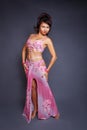 Belly dancer performing belly dance in the ethnic pink costume for dancing on gray background Royalty Free Stock Photo