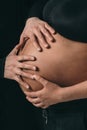 The belly of a pregnant girl is close-up. The husband is careful to hold the belly of the pregnant wife.