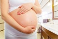 Belly of a pregnant woman in the bathroom