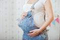 Belly of a pregnant woman in a denim overalls