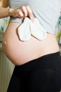 Belly of a pregnant woman holding baby socks. Royalty Free Stock Photo