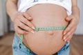 Belly of pregnant woman measuring belly by green centimeter tape. Closeup Royalty Free Stock Photo