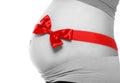 Belly of a pregnant woman tied with a red bow
