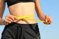 belly of the girl while measuring her waist with the yellow tape Royalty Free Stock Photo