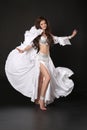 Bellydance. Beautiful belly dancer woman in white shining costume with blowing fabric. Long healthy curly hair. arabian