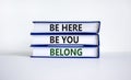 Belong symbol. Books with words `be here, be you, belong` on beautiful white table, white background. Business, belonging and