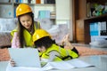 A beloved Asian mother and daughter pretend to be an engineer and smile with a safety hat in the house