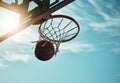 Below, basketball and net with sky in summer for shooting, scoring and points to win game. Hoop, rim and ball in closeup Royalty Free Stock Photo