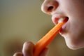 Crop anonymous teenage girl eating fresh organic carrot slice