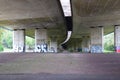 Below a curved highway overpass with graffiti