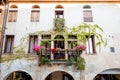 Below frontal view of medieval italian building with flowers and arcade and ivy on the walls on summer day sunset