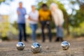 Mature casual diverse pensioners throwing petanque balls far away on a spring sunny day in the park Royalty Free Stock Photo