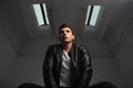 Below view of young man in leather jacket posing seated