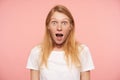 Bemused young lovely redhead woman with casual hairstyle looking surprisedly at camera with wide eyes and mouth opened, isolated