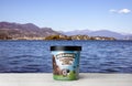 Ben Jerry`s Chocolate Fudge Brownie Ice Cream on white wooden table against blue water and mountains background