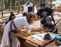 The reconstruction participant of the `Viking Village` helps the visitor to do crafts in the camp in the forest near Ben Shemen in