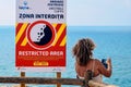 Benagil, Portugal - 04/13/2020: A woman stands behind a fence near a cliff and holds a phone in her hands. Danger while taking pho