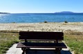 Bench in a beach promenade with grass and vegetation in sand. Blue sea, clear sky, sunny day. Galicia, Spain. Royalty Free Stock Photo