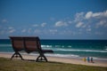 Bench by the beach with surfers in background Royalty Free Stock Photo