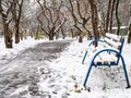 Bench covered by the first snow near footpath Royalty Free Stock Photo