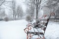 Bench covered with fresh snow on storm day in city park. Royalty Free Stock Photo