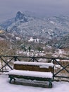 Bench covered in snow and view to Olympus mountains. Litohoro in Pieria, Greece at winter time Royalty Free Stock Photo