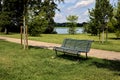 Bench by the edge of a path in a park next to a river on a clear day in summer Royalty Free Stock Photo