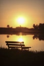 Bench in front of lake in city park with sunset and blurred background, Royalty Free Stock Photo