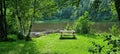 Bench on green grass with lush trees and river flow silent in background Royalty Free Stock Photo