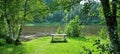 Bench on green grass with lush trees and river flow silent in background Royalty Free Stock Photo