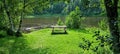 Bench on green grass with lush trees and river flow silent in background Royalty Free Stock Photo