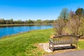 Bench near the beautiful lake with forest reflection on sunny spr Royalty Free Stock Photo