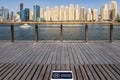 Bench with NO SITTING sign in english and arabic due to COVID-19 safety precautions with Dubai Bluewaters Island skyline.