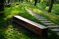 Bench one piece of wood made prism park painted brown footsteps concrete rectangles gray in the lawn and trees Royalty Free Stock Photo