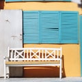 A bench, open door and blue blinds.