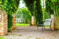 Bench with the overgrown canopy in home landscaped garden in summer. Beautiful flower garden with paving path in backyard