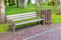 A bench in the park against the background of powerful tree trunks of the city park and green, neatly cut grass Royalty Free Stock Photo