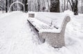 A bench in the park covered with snow in winter Royalty Free Stock Photo