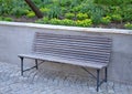 Wooden bench near the edge of the path in the park pedestrian blocks pavement retaining wall low metal frame benches elegant shape