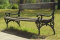 Bench in park with green grass and woods